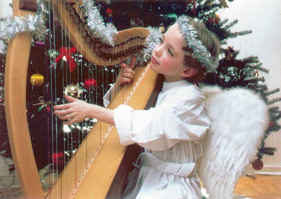 Child in angel costume playing a small harp